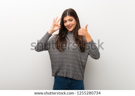 Teenager girl on isolated white backgorund showing ok sign with and giving a thumb up gesture