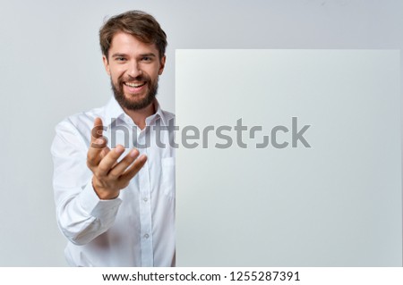 A cheerful man holds in his hands a white paper                   