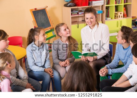 attractive age children sitting and listening smiling teacher at class
