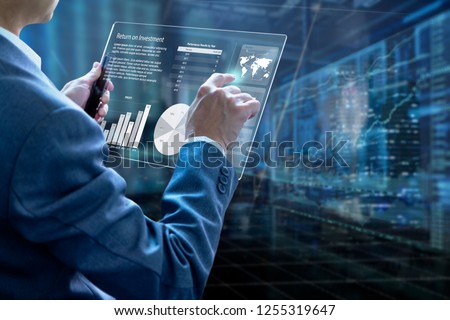 Businessman holding a modern tablet touch screen analysing on investment risk management and return on investment analysis or business performance.