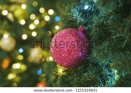 Front view Christmas card. Christmas picture. Bright sparkling pink ball on fluffy branches of Christmas tree. Background bokeh lights of garland. Ready Christmas background. Happy New Year. Glitter