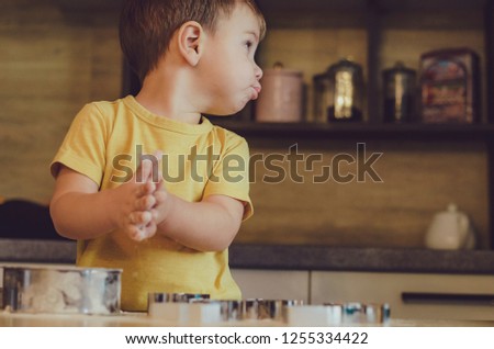 Sweet little cute child boy is learning how to make a cake, in the home kitchen. Concept of family leisure in the kitchen, child preparing food, various dishes. selective focus, noise effect