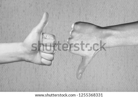 Two hands showing different gestures. Thumb up and thumb down, black and white