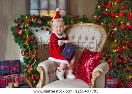 Merry Christmas and Happy Holidays Cute little child girl is decorating the Christmas tree indoors