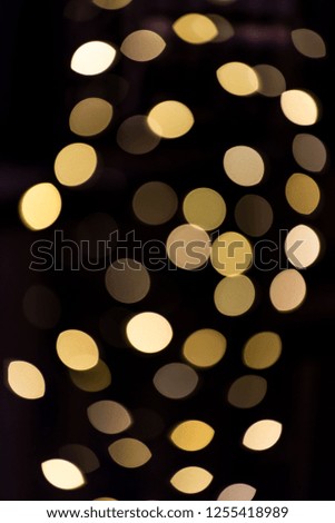 Christmas xmas round bokeh abstract background with yellow golden circles illuminated decoration lights on tree at night evening dark black