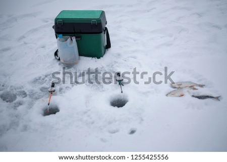 a box with fishing tackle for winter fishing is standing in the snow