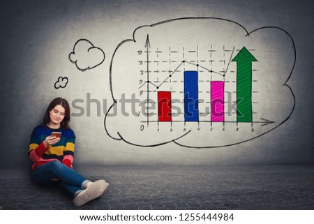 Attractive young woman sitting on the floor using mobile phone imagine a rising graph of virtual sales, cryptocurrency financial business development. Chart shows profit and growth of virtual money.