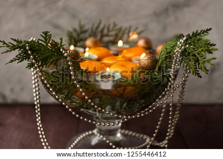 New Year's decor for the home. Decoration for the Christmas dinner. New Year's mood. Tangerines, candles and fir branches in the decor. Selective focus