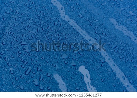 Water drops on a blue cars surface.