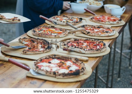 Wood fired pizza at an outdoor reception, being self served.  Royalty-Free Stock Photo #1255475329