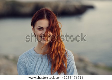 Smiling red-haired woman on the background of nature                    