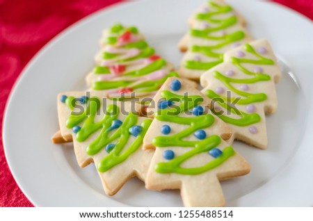 Snowflake and Christmas tree shaped sugar cookies decorated with icing on a white plate