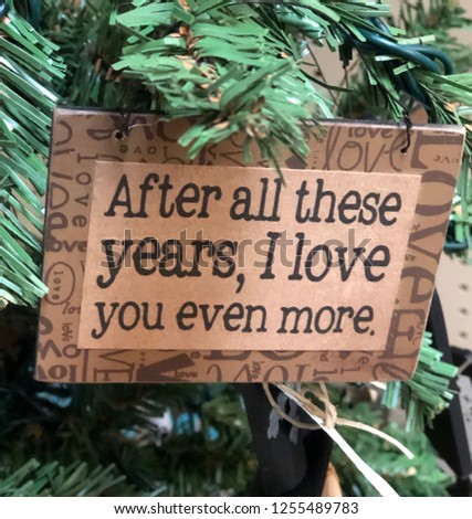 Close up of decorative Christmas holiday ornament hanging in tree with the message - after all these years, I love you even more