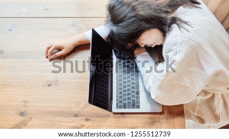 Young woman in bathrobe tired and sleepy on the table at home in front of laptop