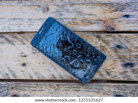 Smartphone left behind, forgotten on old rusty wet table