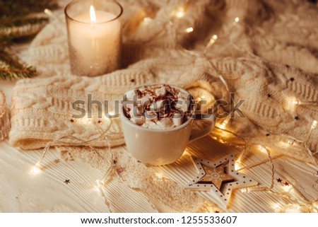Cup of hot cocoa with marshmallows a against rustic background with Christmas fir branches of bokeh. Perfect winter time treat. Toned image. Soft focus.