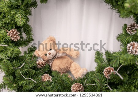 Little bear toy sitting on a pine wreath