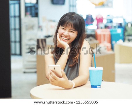 Happy Asian woman using smart phone in outlet mall.