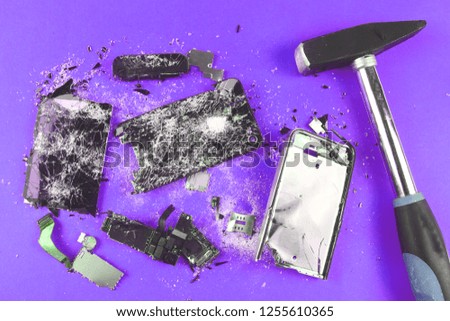 shattered, broken smartphone and hammer on colored background