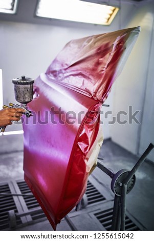 Painting the car door in red color in the painting chamber.