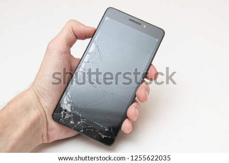 Destroyed smart phone in hand. Cracked display. White background.