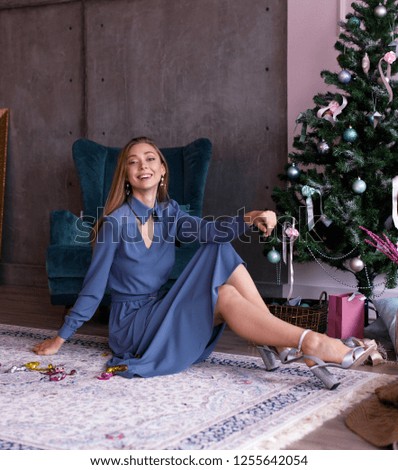 Model girl in a blue dress on a gray background. Christmas holiday atmosphere. Studio photography.