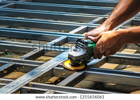 Hands of a man grinding a steel construction with an electric disk grinder for metal