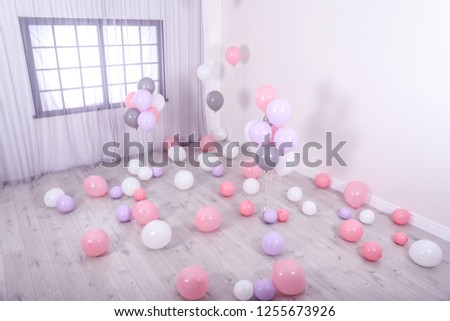 Room decorated with colorful balloons near wall