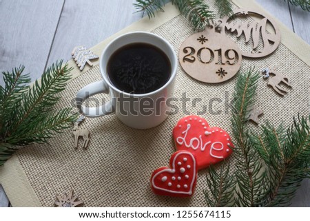 Tinted Christmas picture with 2019 new year on cookies, fir branches, toys, warm scarf and a mug of hot tea on a wooden background