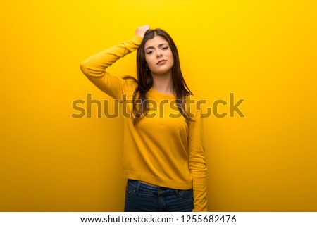 Teenager girl on vibrant yellow background with an expression of frustration and not understanding