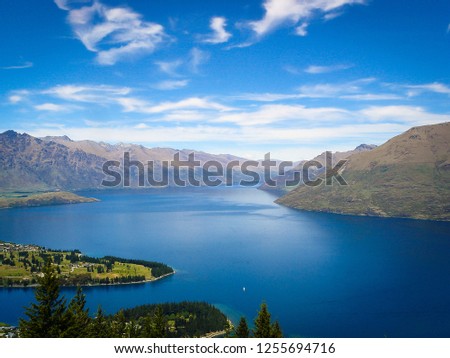 Looking at a lake with clear blue water, the mountains and the cloudy sky in the back