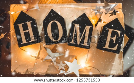 Home decorations in the interior of a letter with an inscription home on a books. Christmas decorations and led string lights. Winter reading. House, comfort