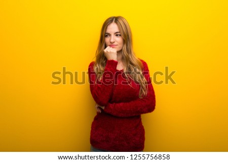 Young girl on vibrant yellow background having doubts