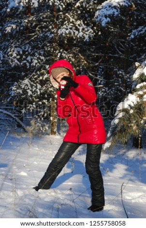 Woman in winter, female photographer takes picture on digital camera outdoors in cold day on blurred forest background, empty copy space, view profile