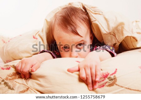 Funny image of happy child girl playing hide and seek under the blanket in her bed room (happy bedtime and good morning, childhood, safety concept).