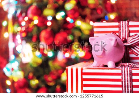 Piggy bank standing on gift boxes against decorated christmas tree