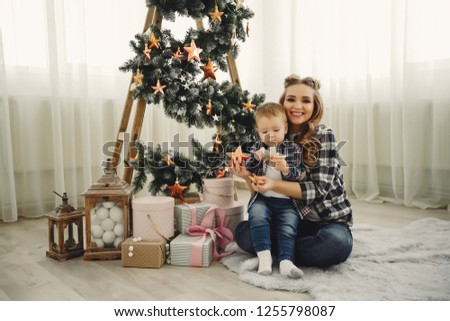 Beautiful family sitting near Christmas tree. Cute mother in a blue shirt