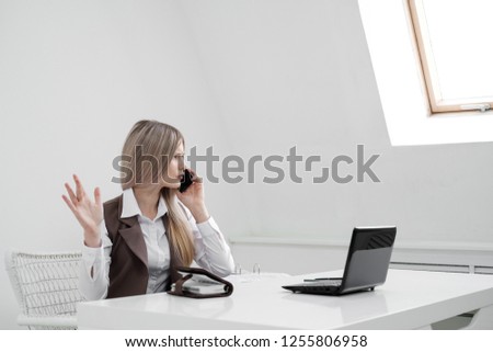 The girl in a business suit and at the desk office worker is annoyed. Shouts on the phone and outraged.