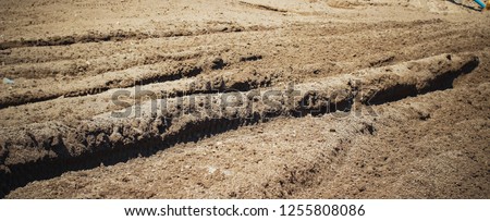 A row of deep brown dirt ruts left behind from a dirt bike race track event.