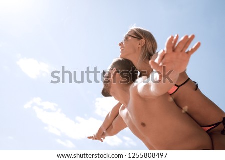 Man carrying woman piggyback on beach.