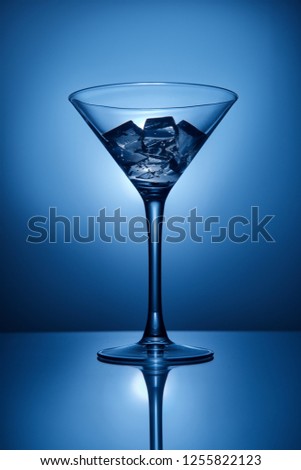 Martini glass with ice on blue background