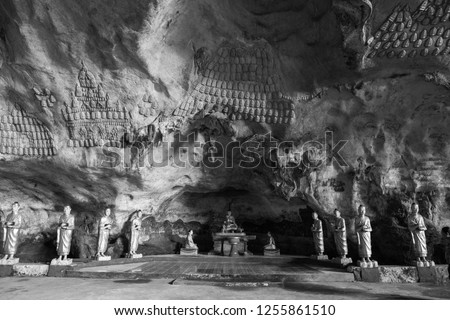 Black and white picture of aligned monks statue and ornated walls inside Sadan Cave, important landmark of Hpa-An, Myanmar