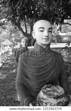 Black and white picture of monks statues, symbol of Offering at Kaw Ka Thaung Cave, located close to Hpa-An, Myanmar