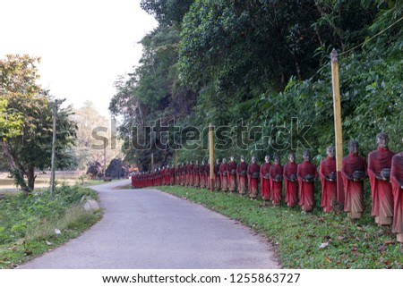 Horizontal picture of many aligned monks statues at the road to Kaw Ka Thaung Cave, located close to Hpa-An, Myanmar
