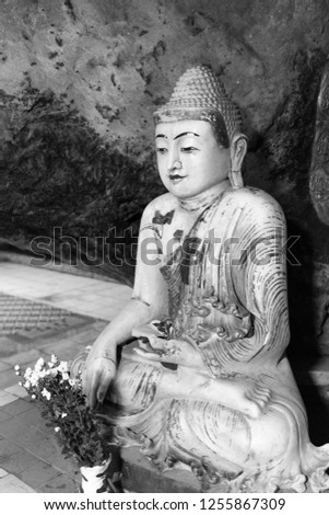 Black and white picture of Buddha statue sitting in meditation position  inside of Kaw Ka Thaung Cave, located close to Hpa-An, Myanmar
