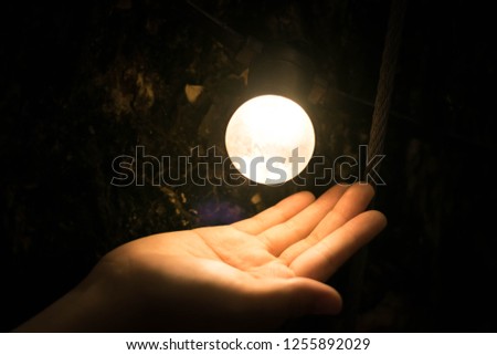 hand holding and light bulb with darkness and light