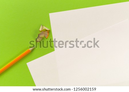 Pencils with sharpening shavings with white paper sheets on coloured backgroung, Office tool