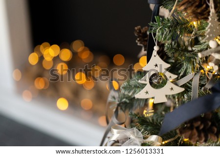 Christmas tree decorated with wooden toys. On the background of a blurred fireplace. Selective focus