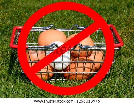 Chicken eggs in a shopping basket on the grass with a no entry sign in the foreground, UK.
