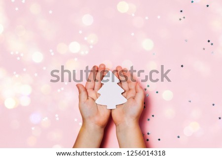 Child's hands holding big snowflakee in hands on sparkling pink background. Bright and festive Christmas and New Year picture. Top view, flat lay.